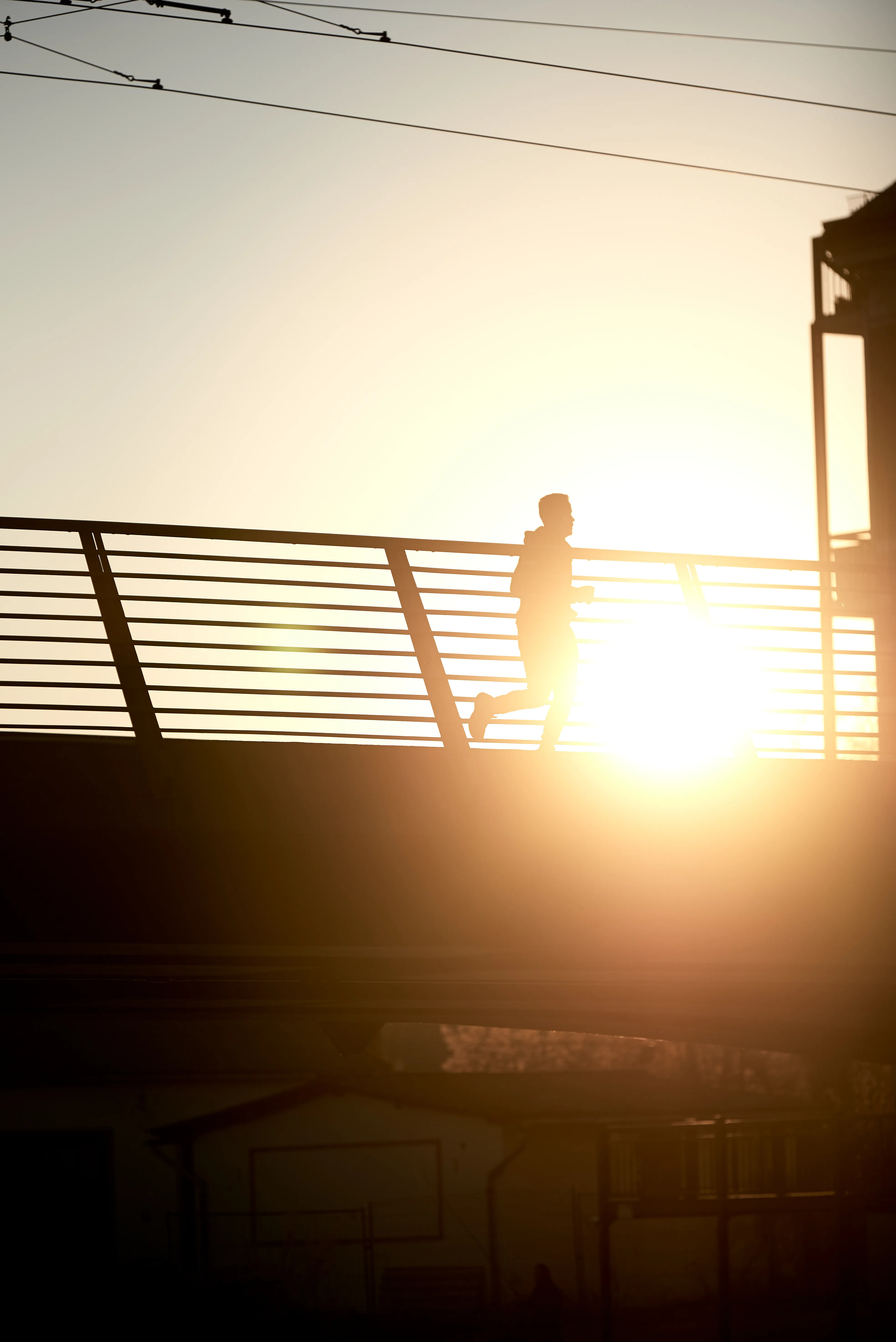 Jogger-Silhouette auf einer Brücke in Brandenburg an der Havel im Gegenlicht der untergehenden Sonne — Bewegung, Klarheit, Richtung.